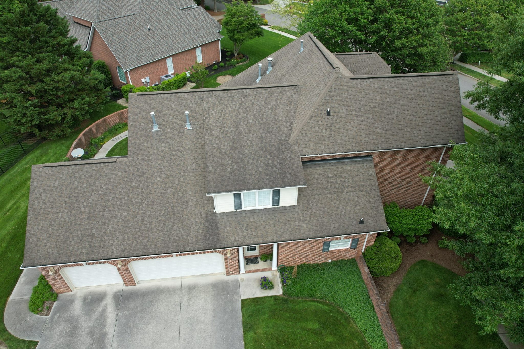 Dark Streaks on an Asphalt Shingle Roof in Halls Aerial view of a brick home with dark streaks across its gray asphalt shingle roof.