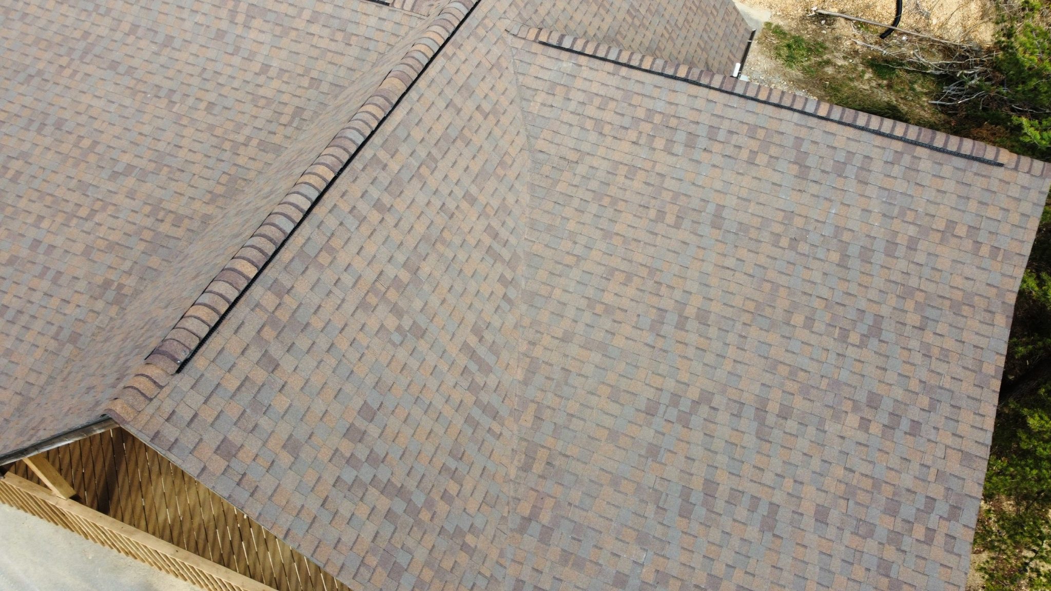 Shingle Roof Ridges and Intersecting Slopes Overhead view of brown and gray shingles along intersecting roof ridges.