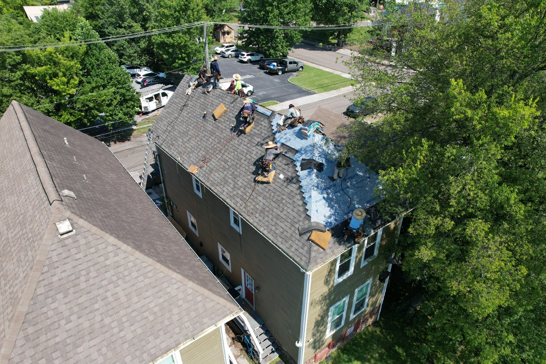 Roofing crew installing OSB sheathing and new shingles on an older Downtown Knoxville roof.