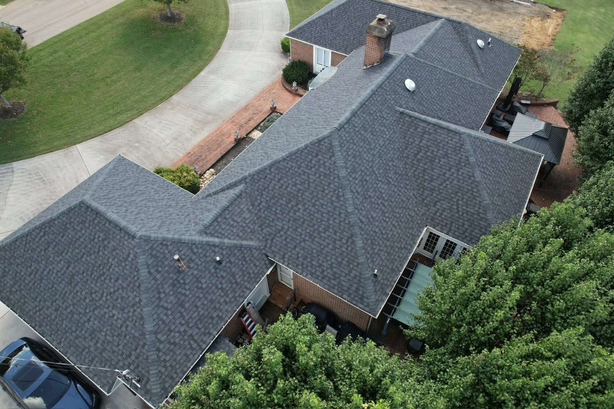 Knoxville Roof by Local Roofing Contractor Aerial photo of a Knoxville brick house with a dark gray architectural shingle roof installed by a local roofing contractor, showing ridges, valleys, and vents.