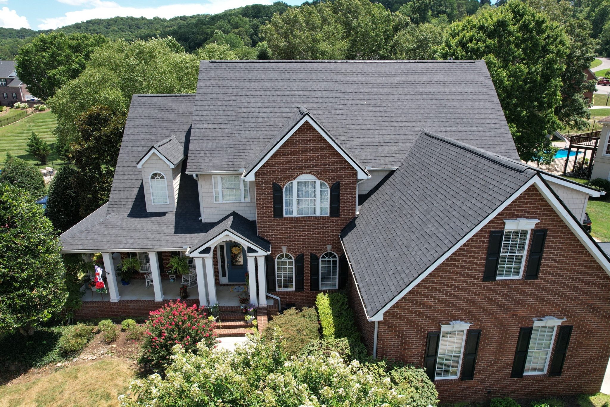 Brick Knoxville home with a dark asphalt shingle new roof, shown from an aerial view.