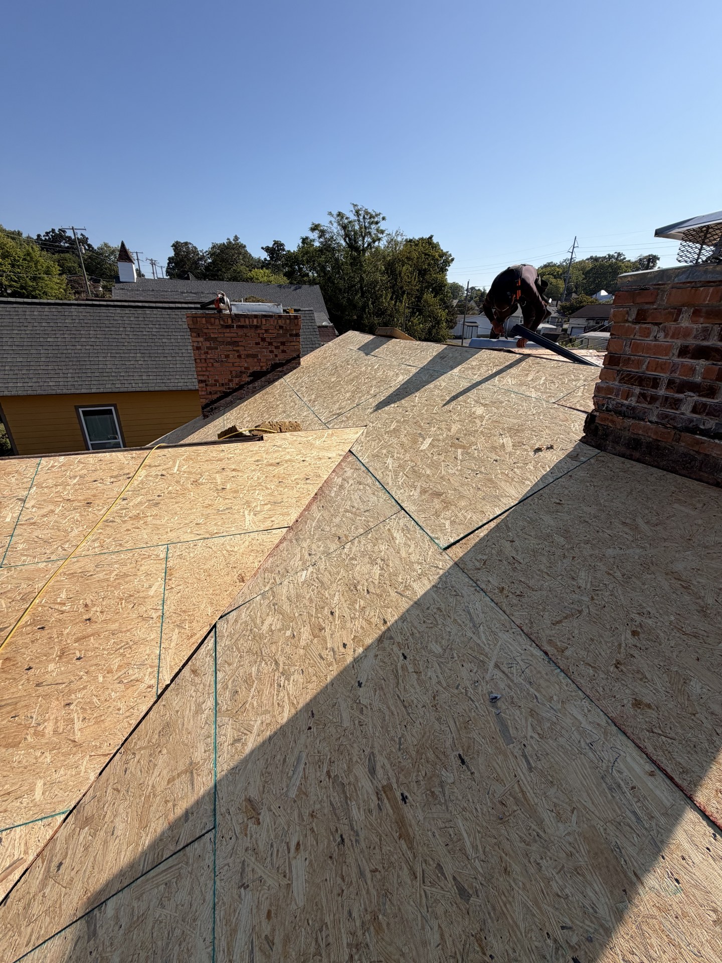 New OSB roof decking installed across the roof slopes around the brick chimney.