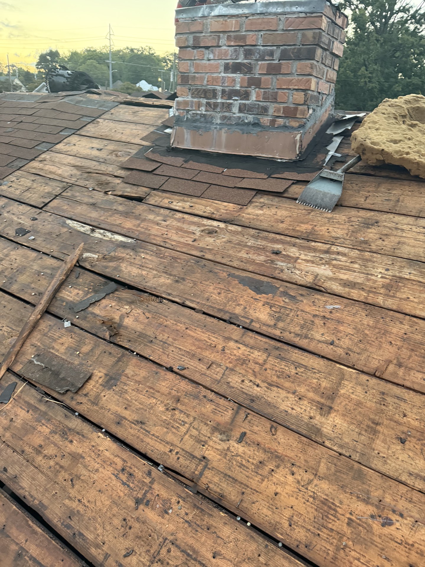 Exposed wood roof planks with visible gaps between the boards during tear-off.