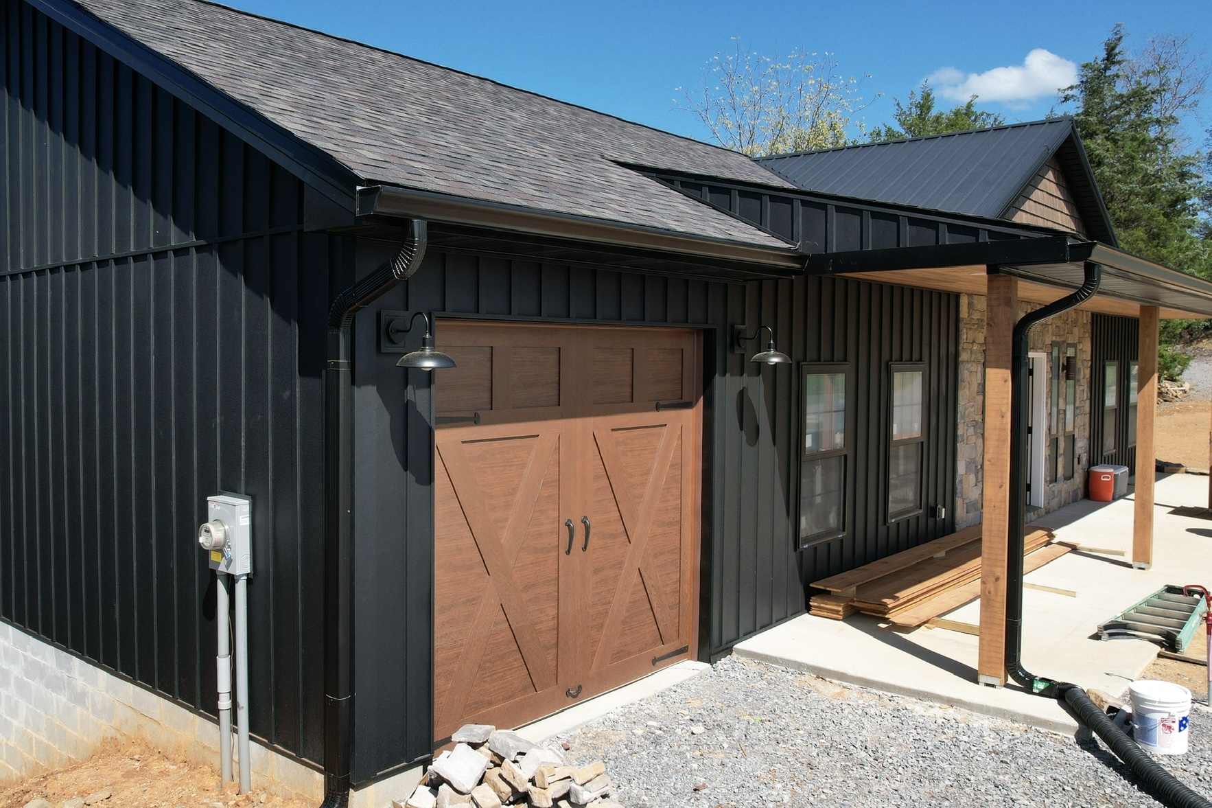 Close view of black oversized gutters with 3x4 downspouts installed on a modern black-siding home in East Tennessee, showing new seamless runs at the eaves.