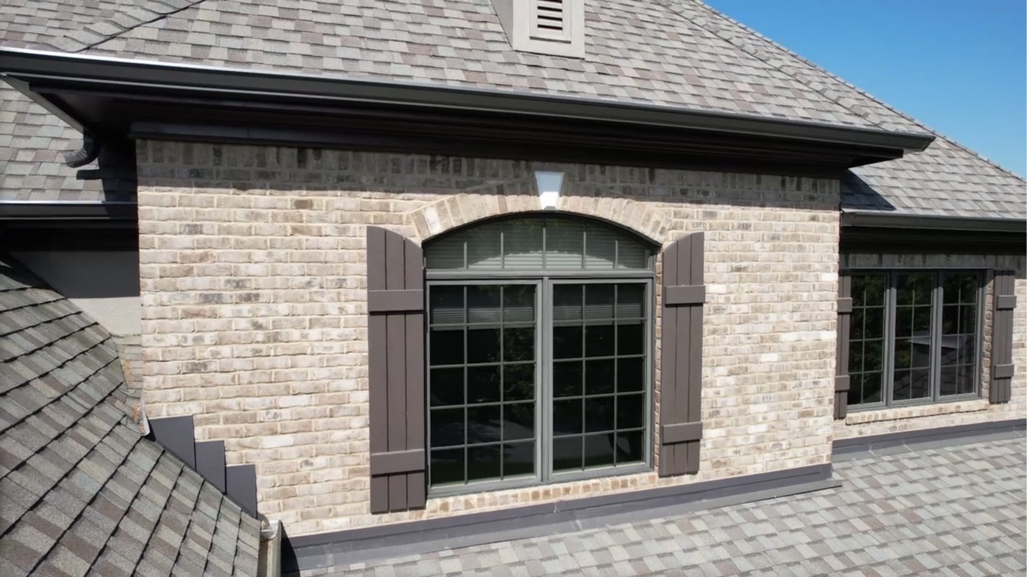 Step and headwall roof flashing installed where an asphalt shingle roof meets a brick dormer.