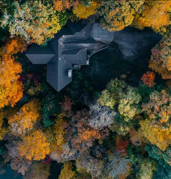 Smoky Mountain Home Photo taken from above. Shows the roof of a large home surrounded by autumn trees in the Smokey Mountains.