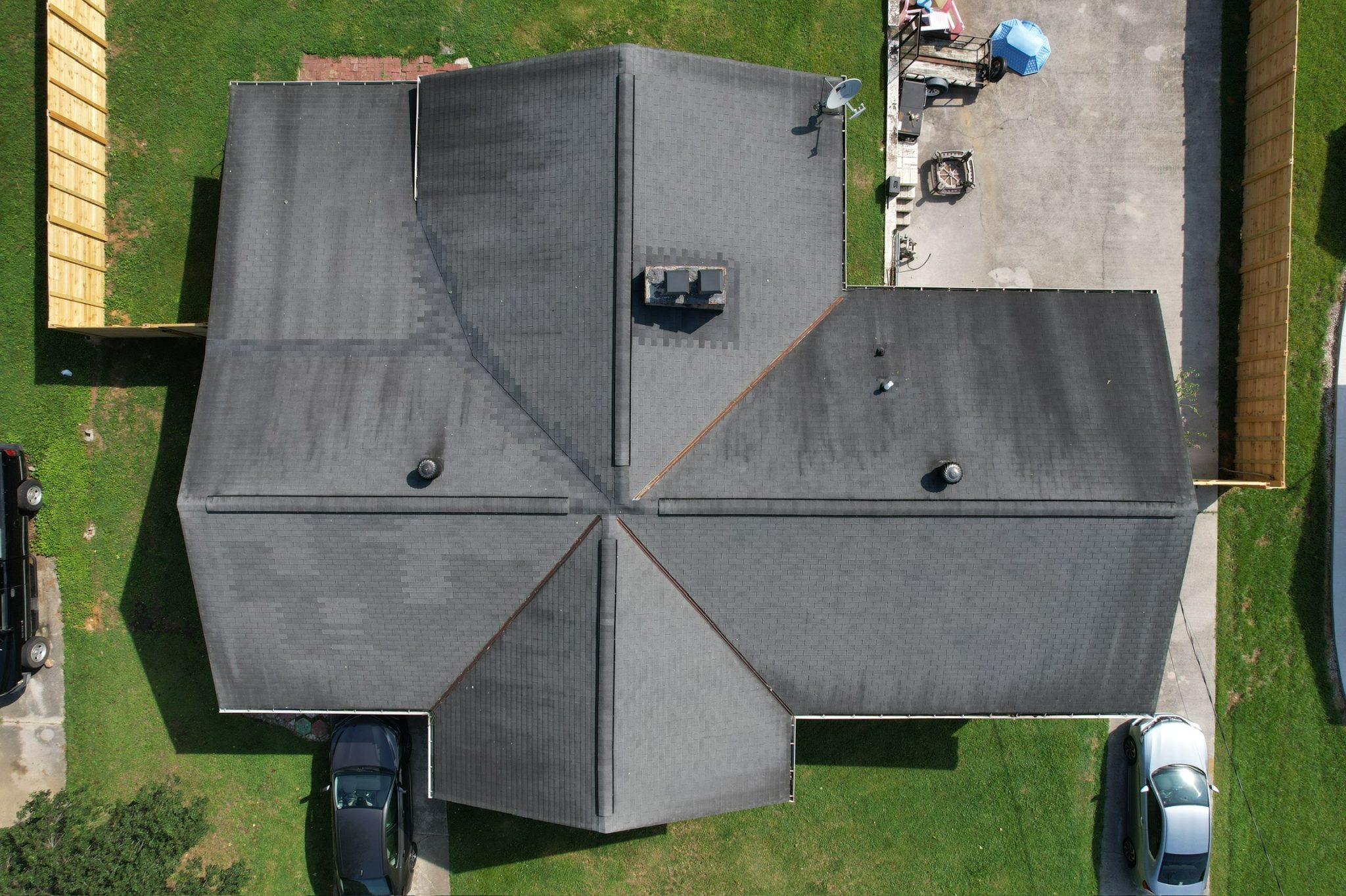 Aerial View Showing Wear on Asphalt Roofing Overhead photo of asphalt roofing with algae streaking, worn valleys, ridge vents, and aging shingles across multiple roof sections.