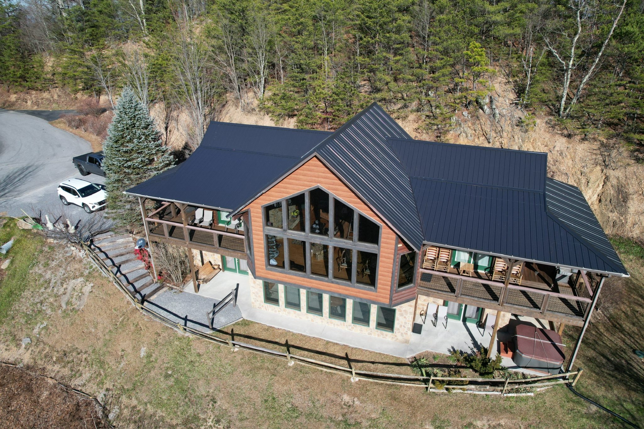New Metal Roof Replacement on a Mountain Home in East Tennessee Aerial view of a modern mountain home with a newly installed black standing seam metal roof, surrounded by trees in East Tennessee.