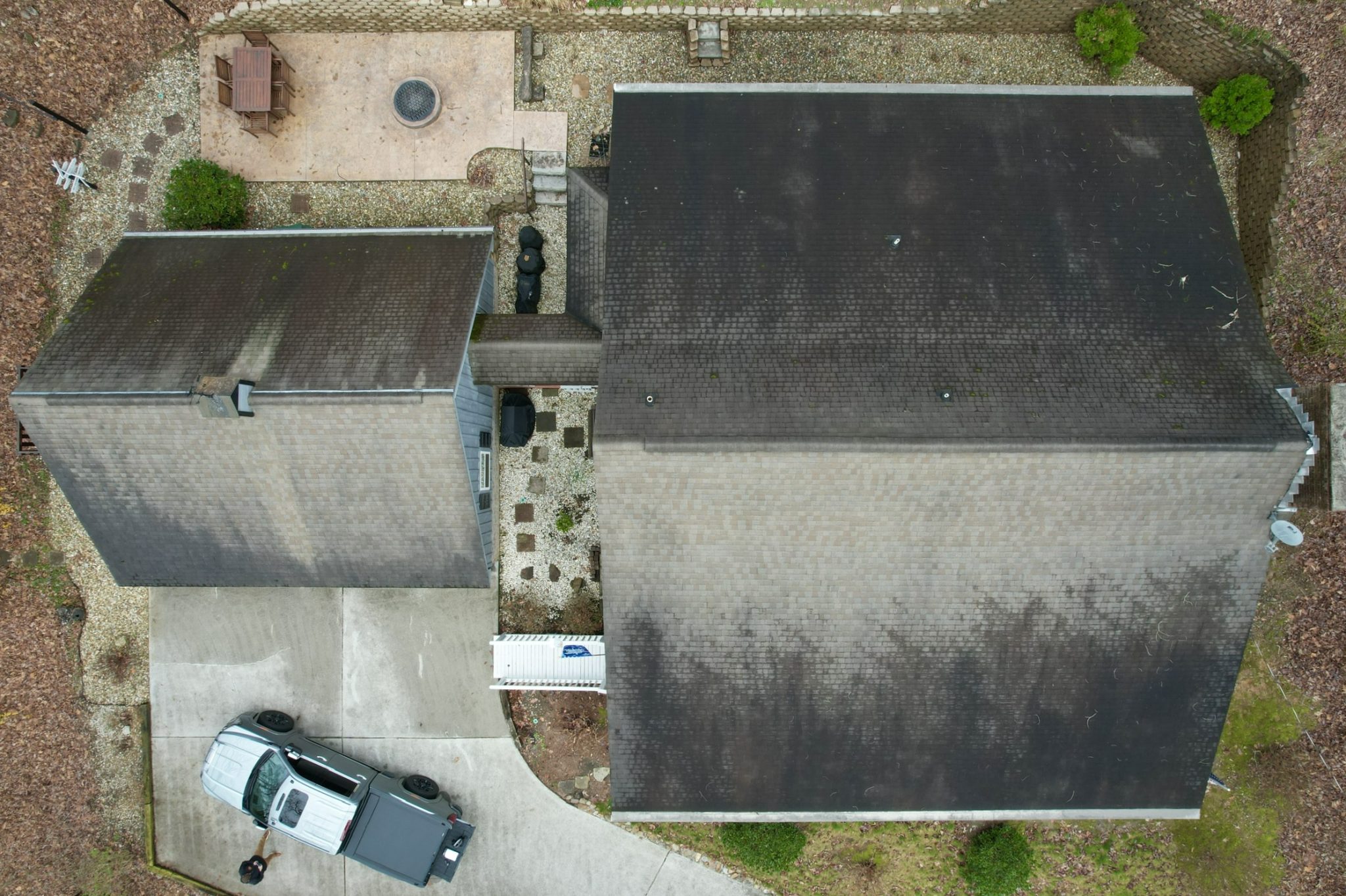Roof with algae and moss growth in East Tennessee. Aerial view of asphalt roof with visible algae and moss buildup in shaded areas.