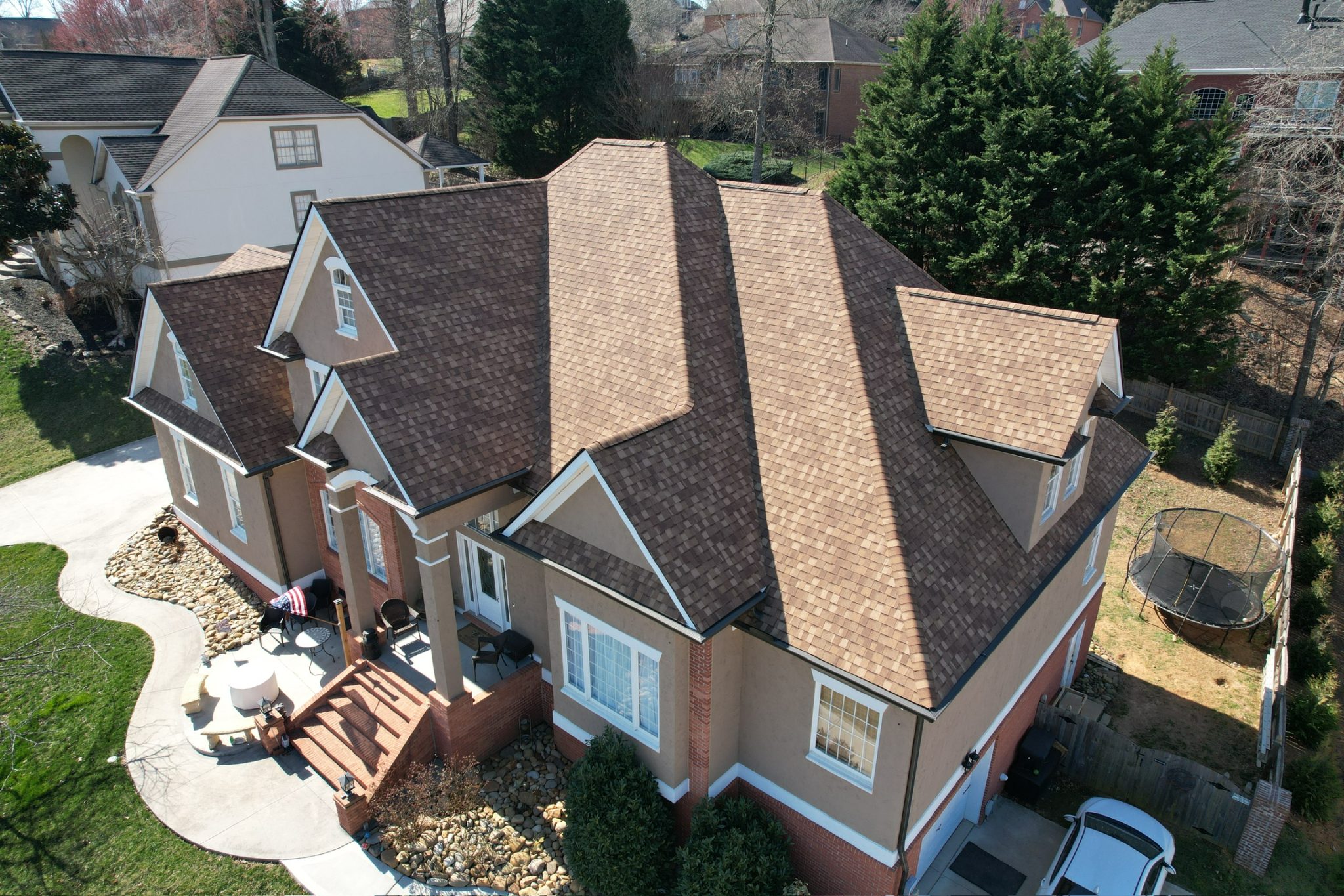 Freshly Completed One-Day Roof Installation Aerial view of a large house with a freshly installed brown asphalt shingle roof after one-day roof installation.