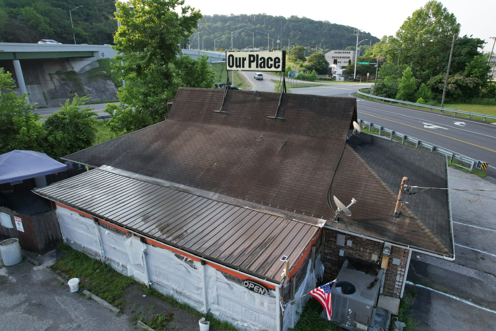 Roof Repair Needed on Commercial Building Aerial view of a commercial building with dark stains and visible wear on asphalt shingles, showing signs of roof damage in need of roof repair or replacement.