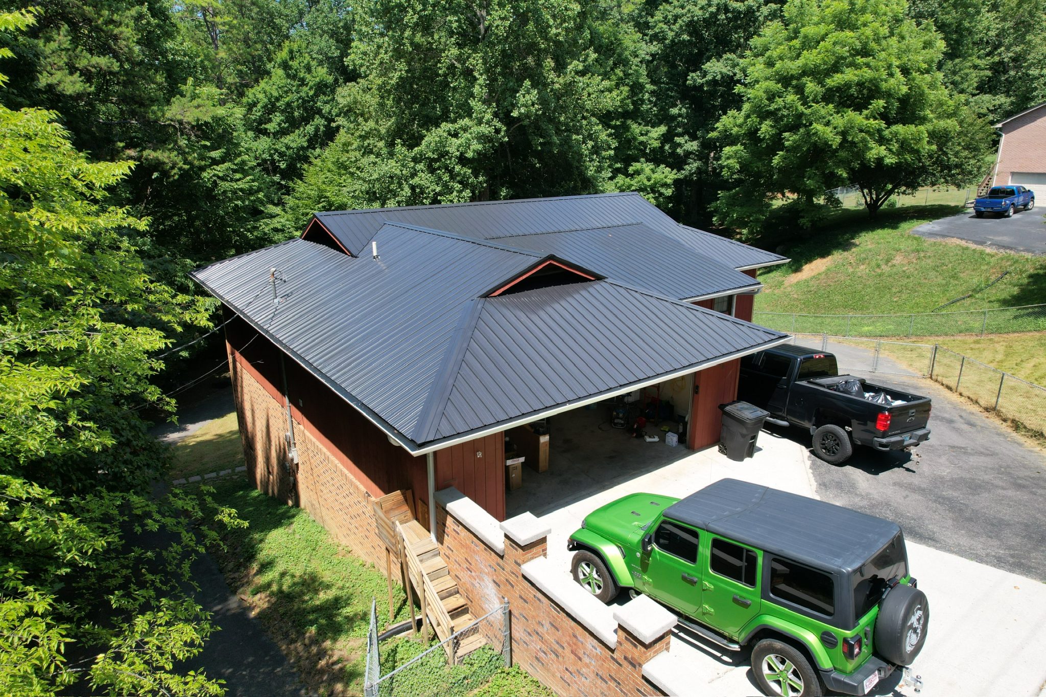 Metal roof maintenance on a Knoxville, TN home with a black standing seam metal roof viewed from above.