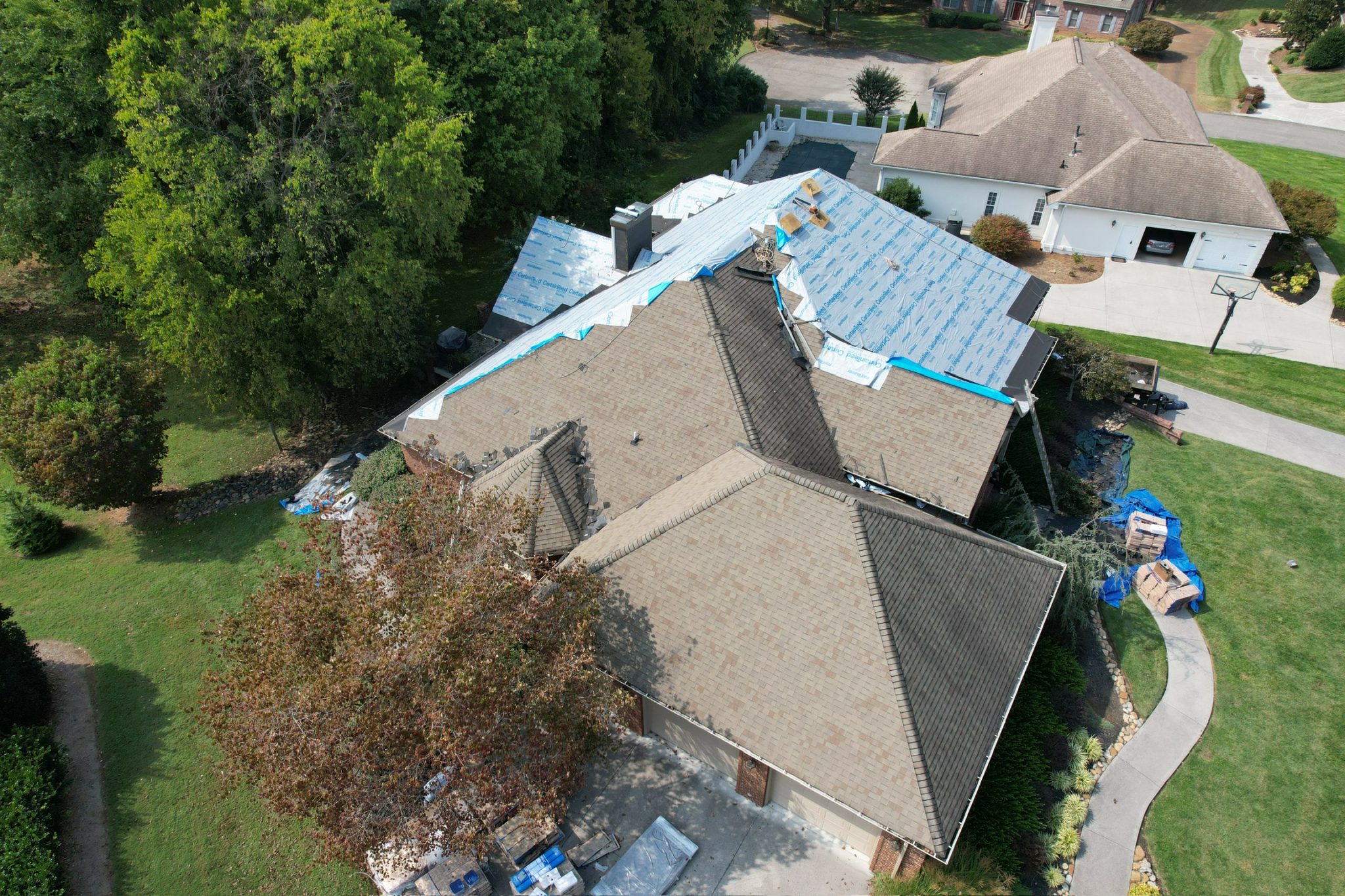 Can You Roof Over Old Shingles in Tennessee: Rules and Risks Can You Roof Over Old Shingles in Tennessee: aerial view of an asphalt roof tear-off with synthetic underlayment installed before new shingles.