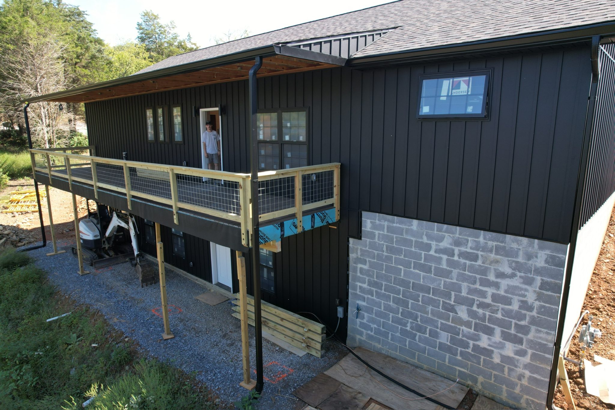 Gutter Replacement Cost Factors in Knoxville: What Drives Pricing Gutter replacement cost factors in Knoxville shown on a black board-and-batten home with a visible gutter run and downspout along the roofline.