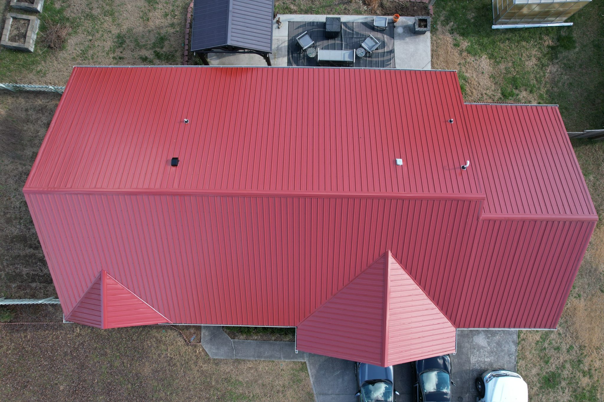 Can a Metal Roof Go Over Shingles in Tennessee: aerial view of a red tuff rib metal roofing system on a residential home.