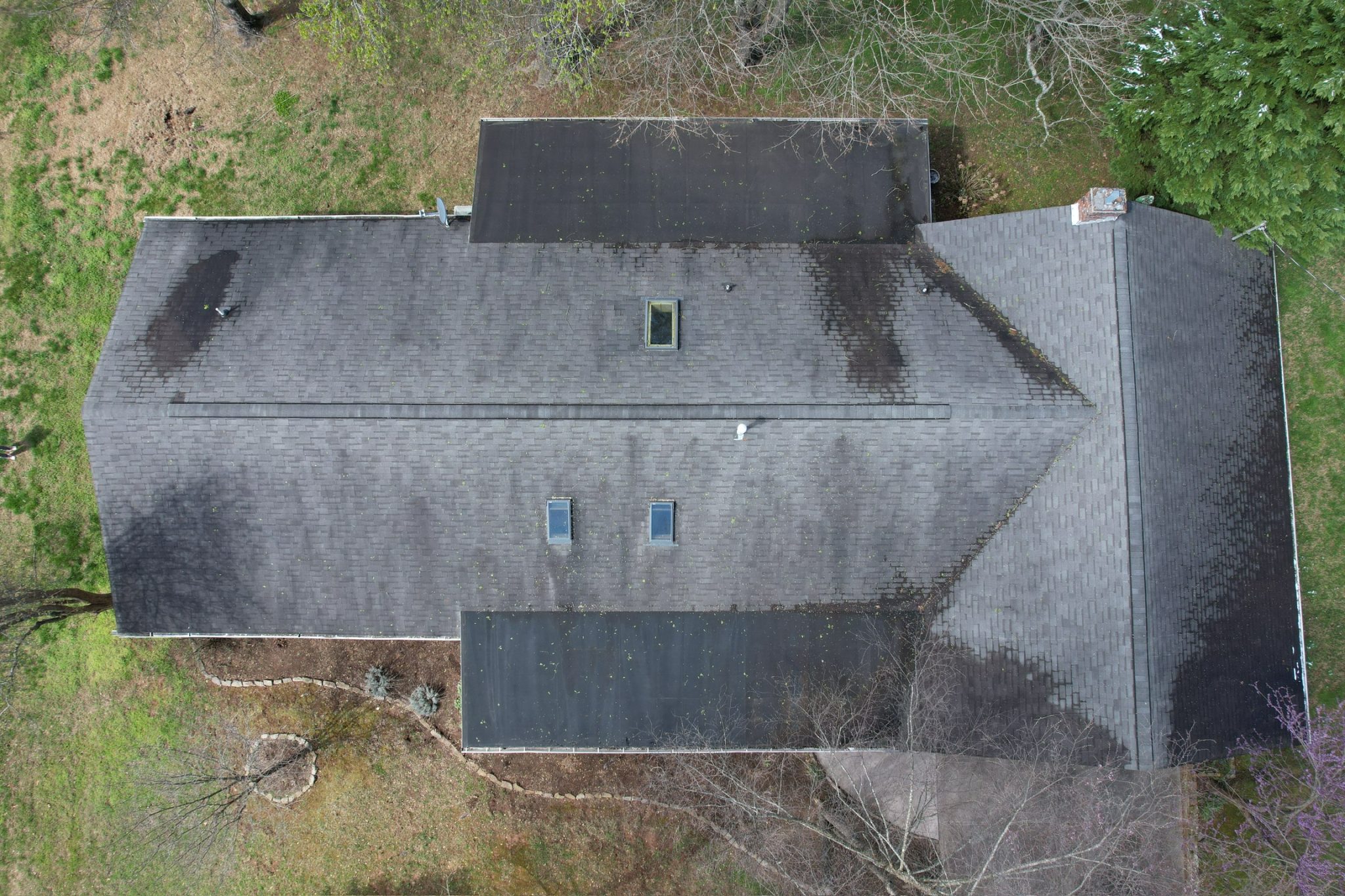Aerial view of an old, dirty shingle roof showing dark streaks, debris, and wear as part of spring roof maintenance in East Tennessee.