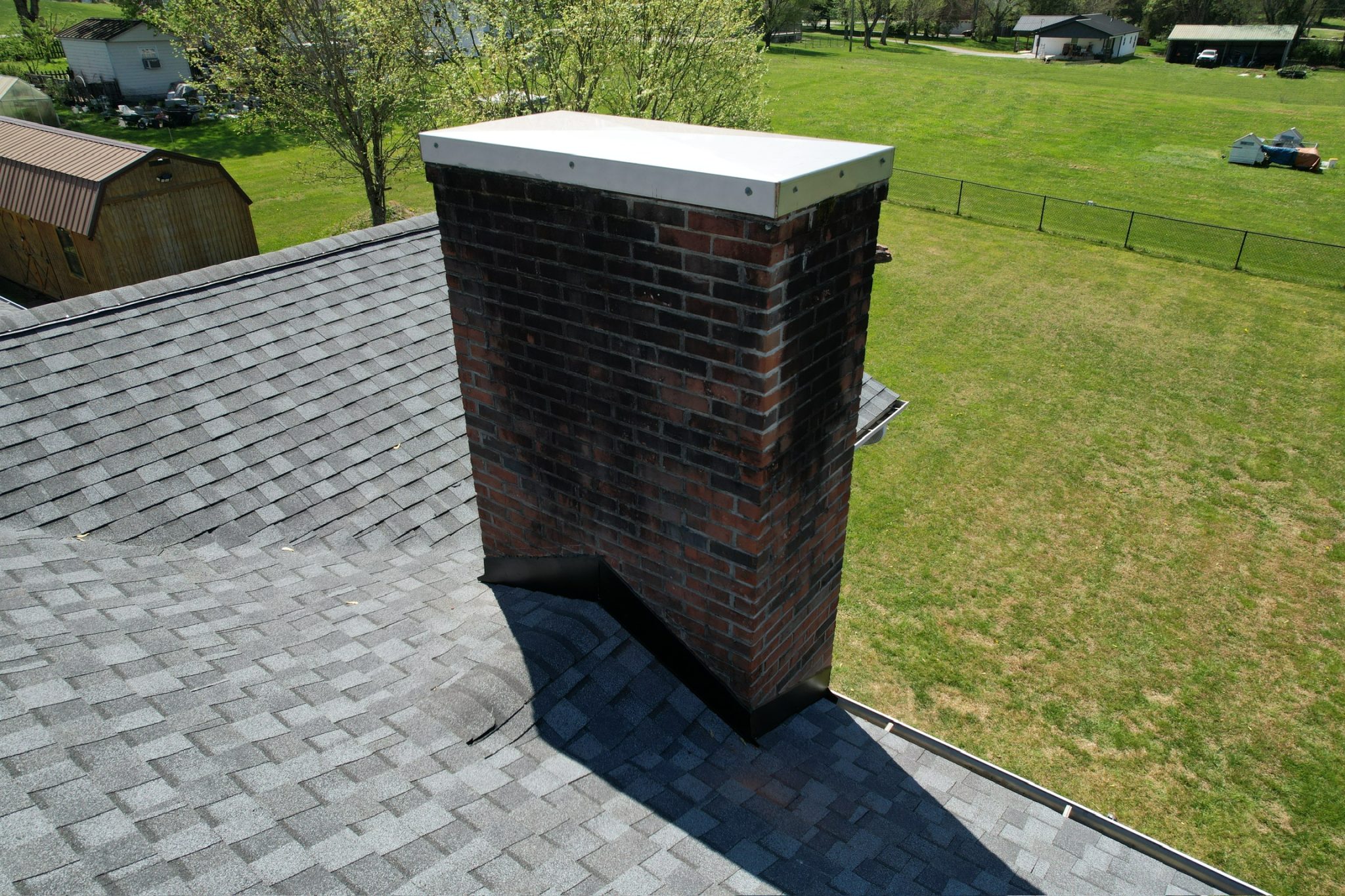 Roof flashing installed around a brick chimney on an asphalt shingle roof.