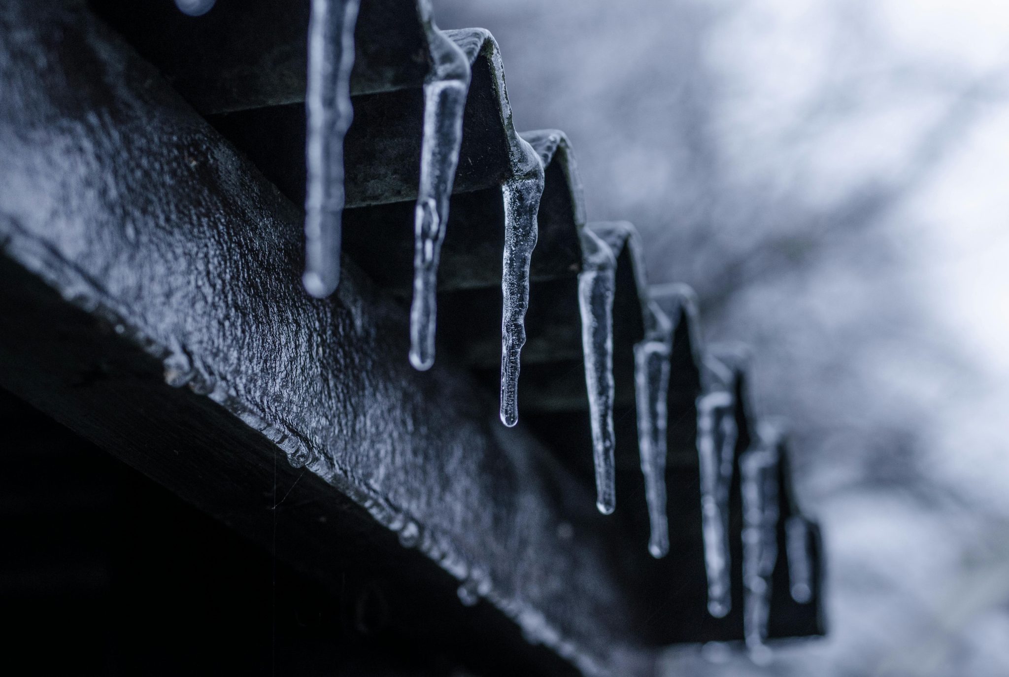 Get Your Roof Ready Before the First Freeze Icicles hanging from a roof eave, illustrating why you should Get Your Roof Ready Before the First Freeze.